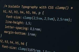 CSS code displayed on a laptop screen showing clamp based scalable typography settings.