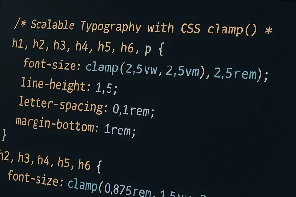 CSS code displayed on a laptop screen showing clamp based scalable typography settings.